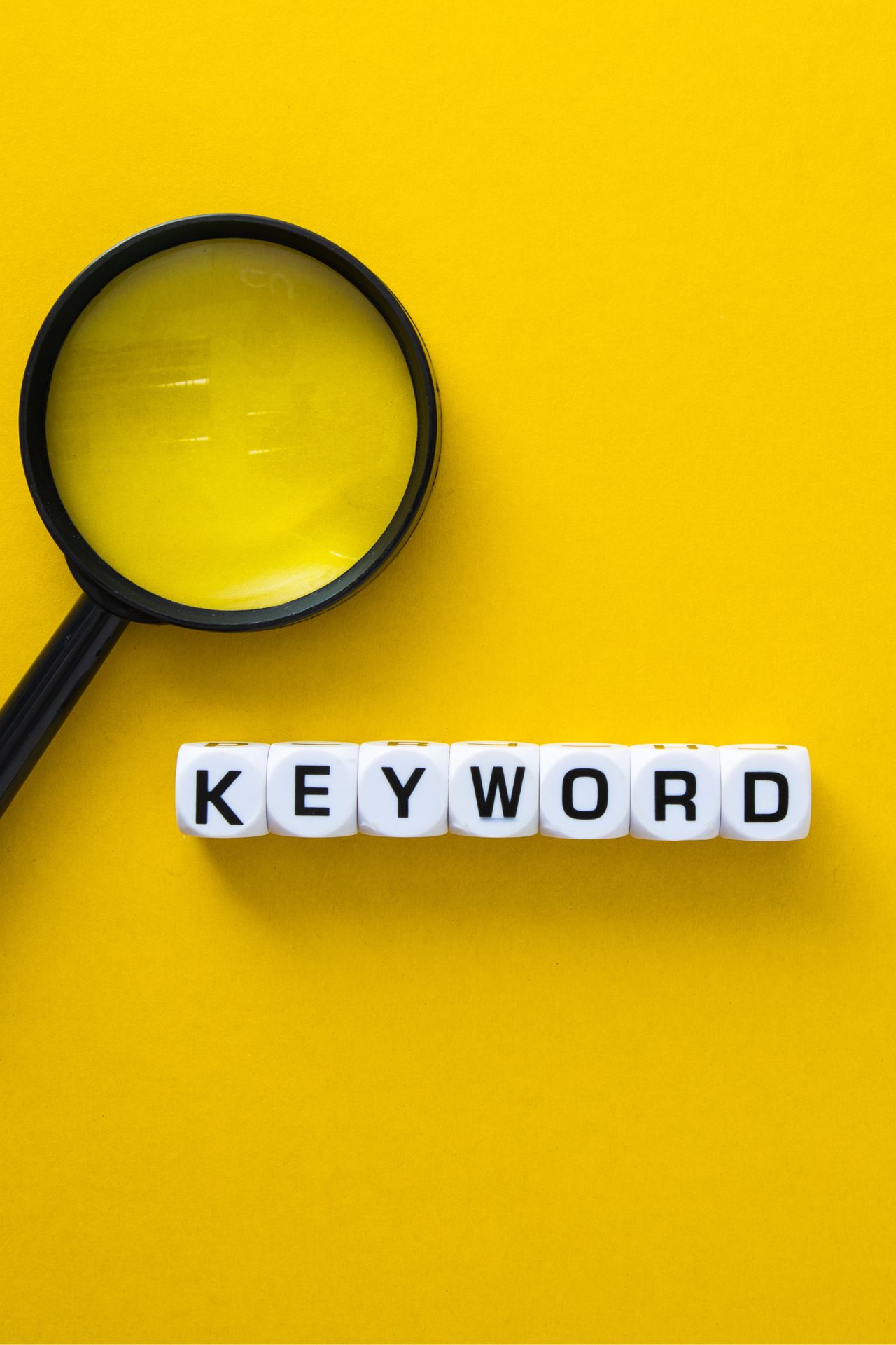 Lupa junto con dados que muestran la palabra Keyword